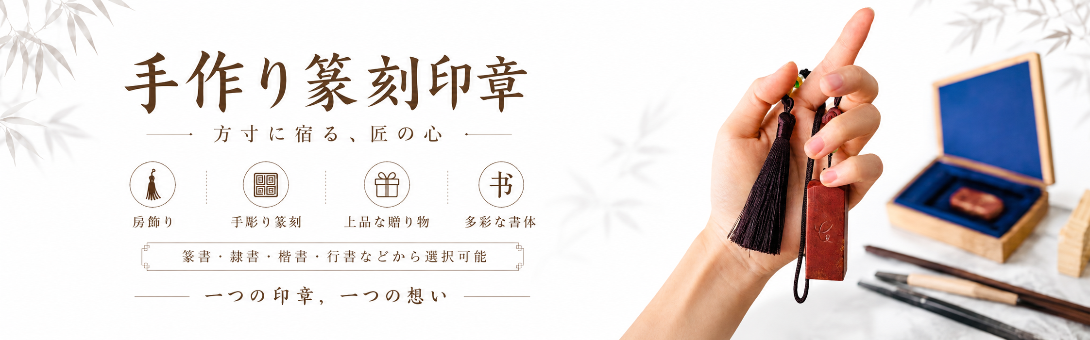房飾り付きの印章を手に持ち、奥にギフト箱と筆を置いた参考ビジュアル